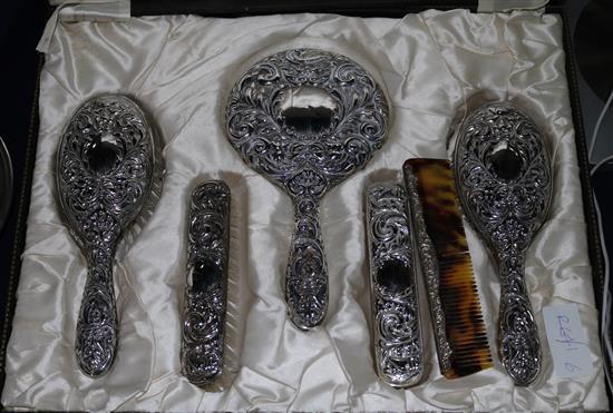 A cased six piece repousse silver brush set.